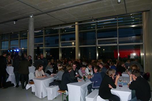 Teilnehmer der DGSA Tagung sitzen im Foyer des neuen Gebäudes am Campus der Hochschule Düsseldorf an Tischen und diskutieren.