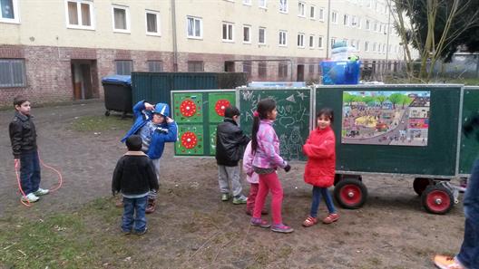 Kinder spielen am Anhänger der Mobile School