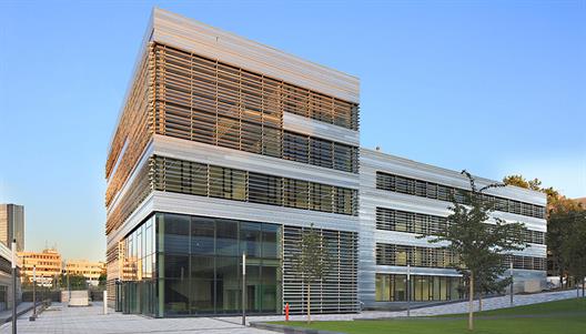 Dieses Bild zeigt das Gebäude der Fachbereiche Sozial- und Kulturwissenschaften und Wirtschaftswissenschaften. Innen ist das Gebäude mit grünen Elementen versehen, außen besteht das Gebäude aus Glas und Stahl.