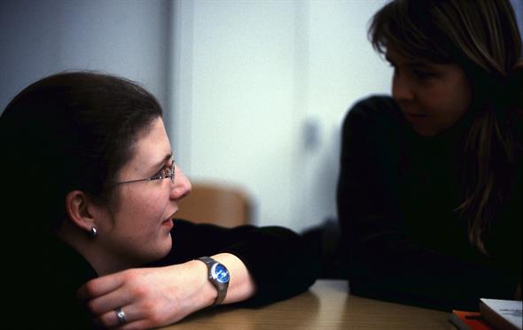 Zwei Frauen in schwarzem Pullover unterhalten sich an einem Tisch