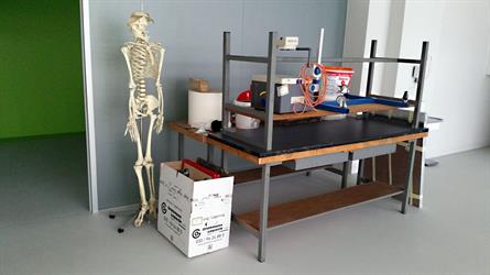 Gestapelte Tische mit Farbeimern und ein Skelett