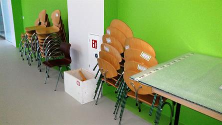 Gestapelte Stühle im Flur mit grüner Wand