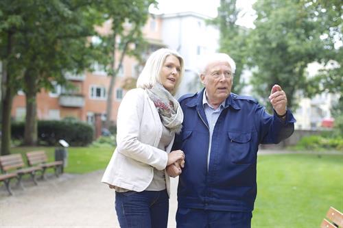 Eine Frau im Alter von ca. 40 bis 50 Jahren stützt einen älteren Mann zwischen 70 und 80 Jahren. Die beiden befinden sich auf einem Spaziergang durch einen Park. (Foto: berufundfamilie gGmbH)