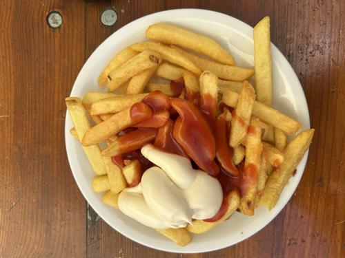 Pommes mit Mayonnaise und Ketchup auf einem Teller auf einem Tisch
