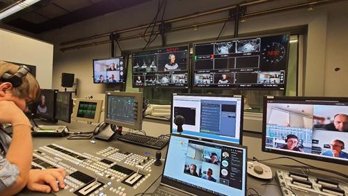 The picture shows a view of a studio from which the hybrid advisory board meeting of the TiWo project is controlled and broadcast. In the foreground sits a person operating the buttons on the control board.